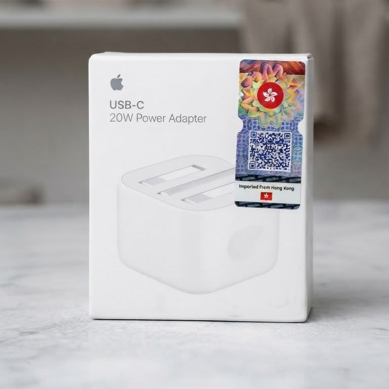 Apple USB-C 20W Power Adapter retail box on a light marble surface with a softly blurred indoor background.